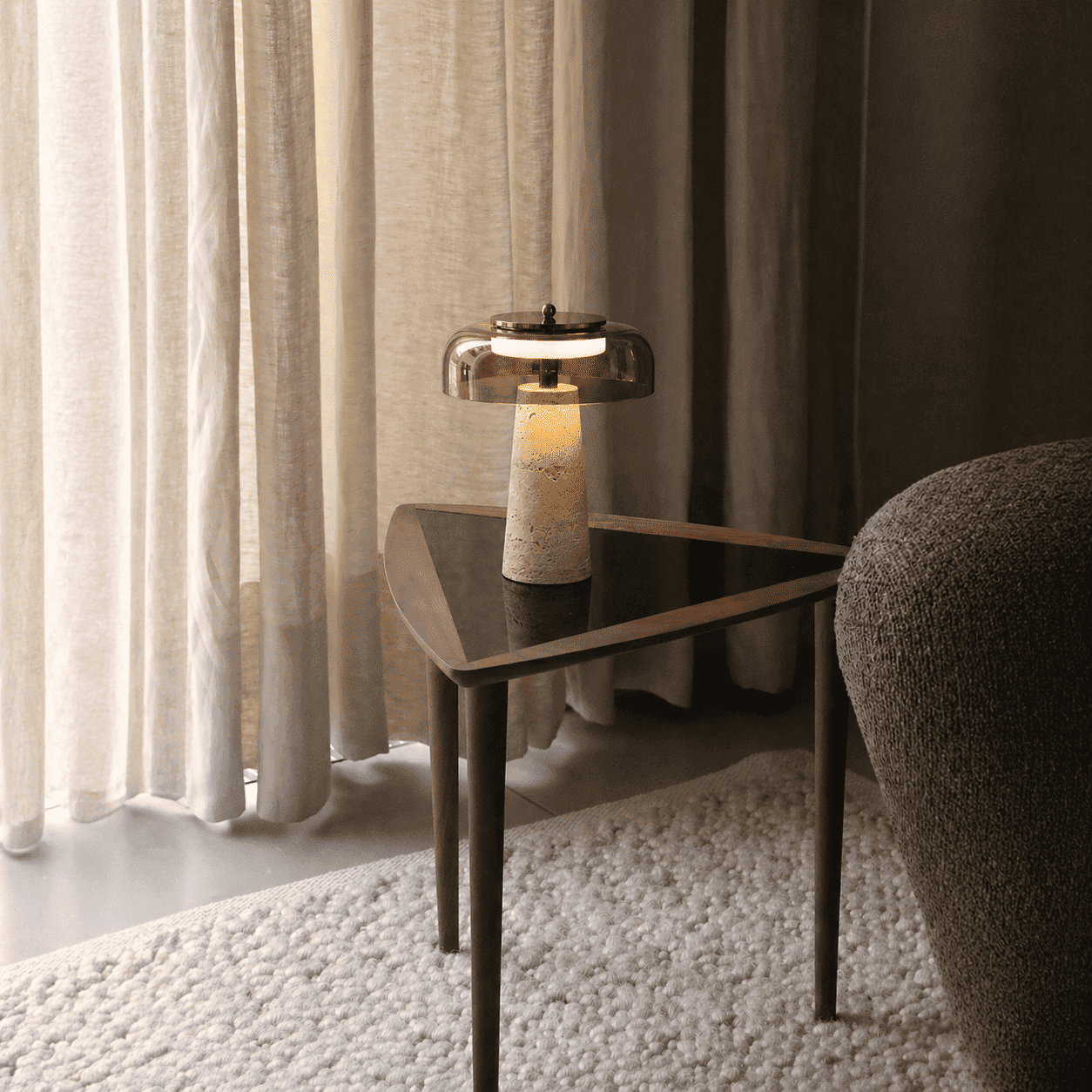 Aeris stone table light on a side table with a soft warm glow in a calm interior