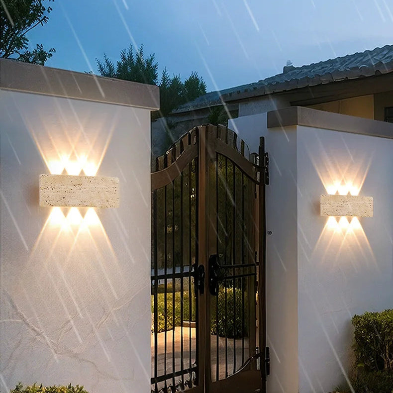 Aure stone wall light adding warm ambient glow to an exterior wall setting