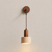 Cael wood wall light with a round wood wall mount, suspended cord, textured shade, and warm downward glow