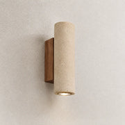 Elden travertine wall light with a warm downward glow on a textured neutral wall