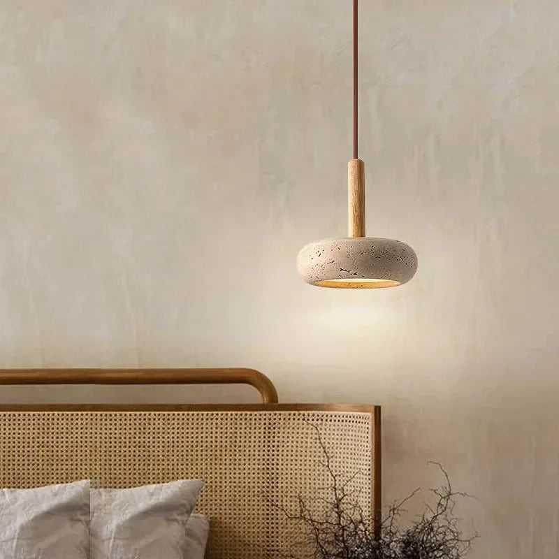 Lume stone pendant light creating warm ambient light beside a neutral bedroom wall
