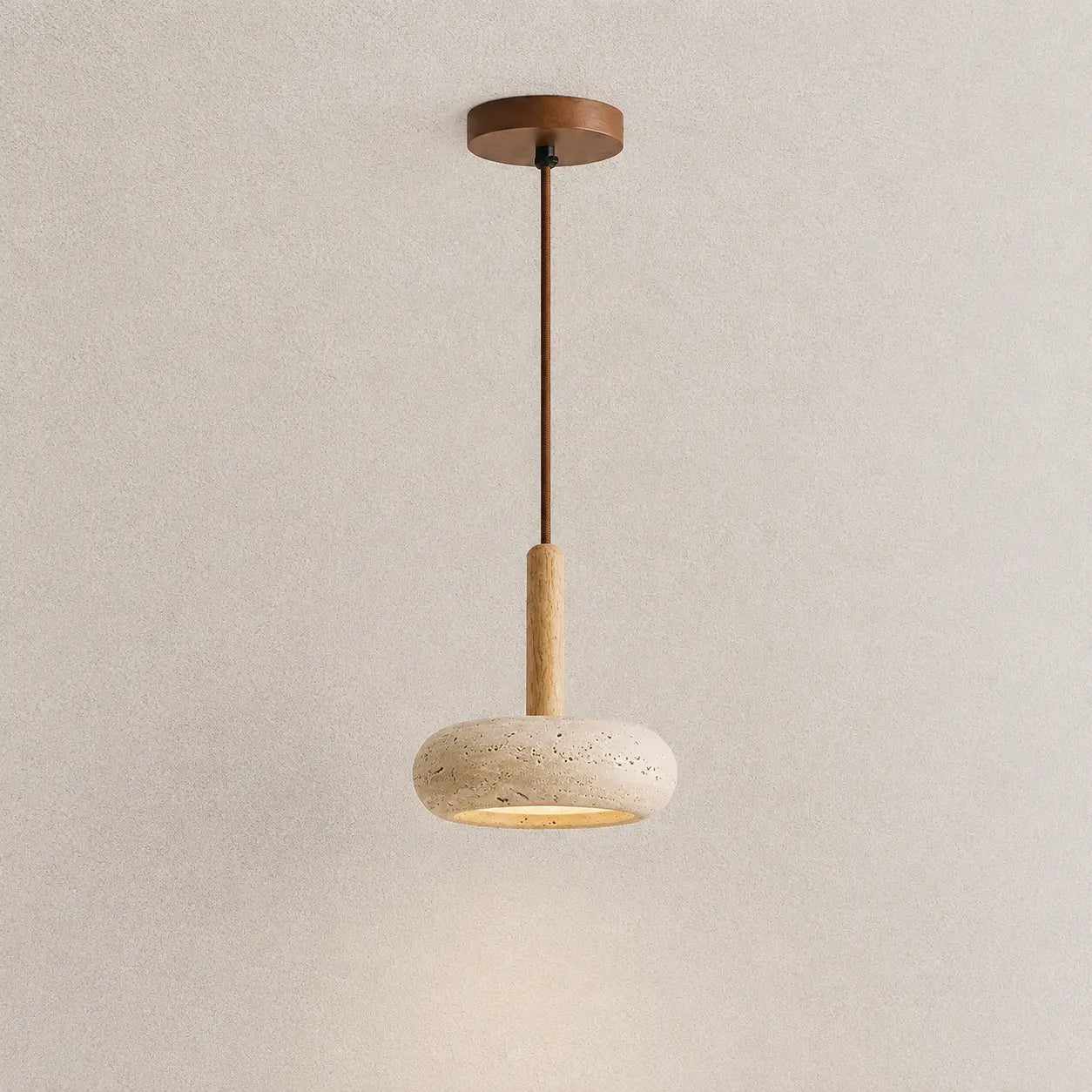 Lume stone pendant light with a slim wood stem, textured stone shade, and warm downward glow