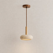Lume stone pendant light with a slim wood stem, textured stone shade, and warm downward glow