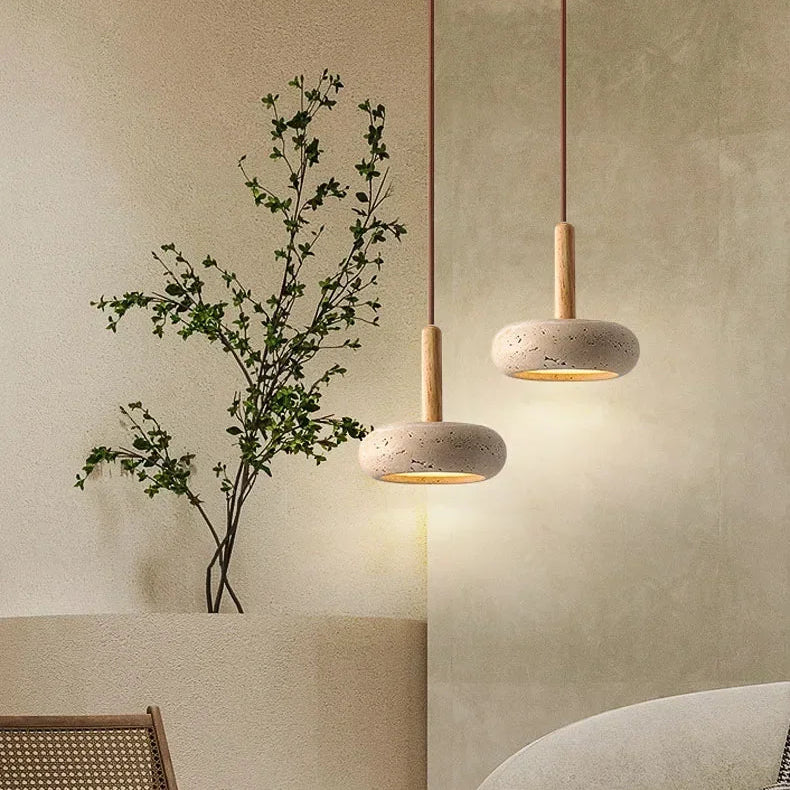 Lume stone pendant light adding a quiet warm glow beside a plant on a small table