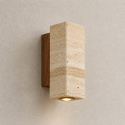 Niva travertine wall light with a soft warm downward glow on a neutral textured wall