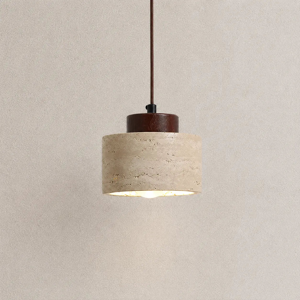 Selo stone pendant light with a textured stone shade, dark wood top detail, and warm downward glow