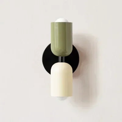 Solvi macaron wall light in green and black with a soft glowing shade and compact wall-mounted form