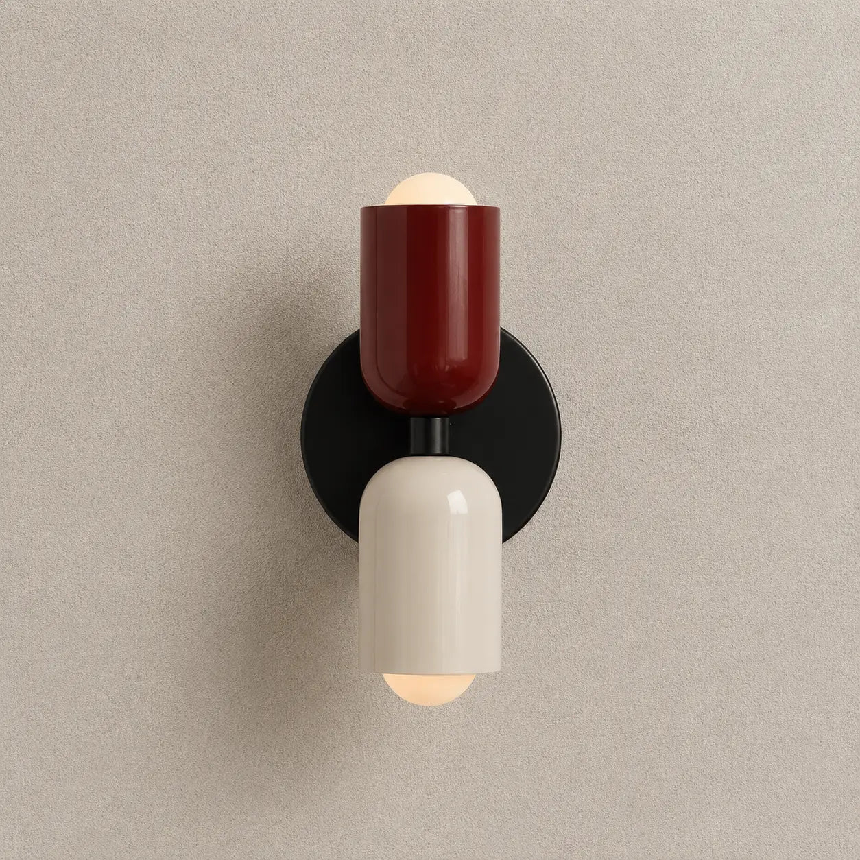 Solvi macaron wall light with red and black color accents, rounded wall-mounted design, and soft downward glow