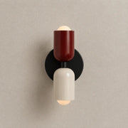 Solvi macaron wall light with red and black color accents, rounded wall-mounted design, and soft downward glow