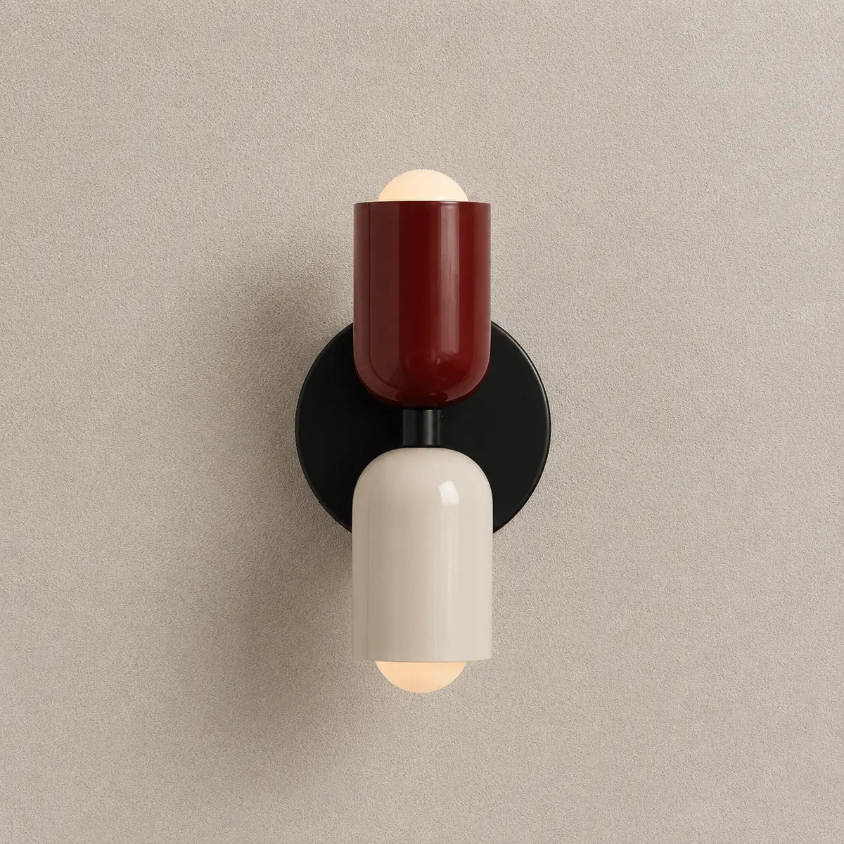 Solvi macaron wall light with red and black color accents, rounded wall-mounted design, and soft downward glow
